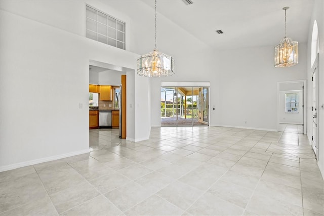 spare room featuring a towering ceiling, an inviting chandelier, and light tile patterned flooring