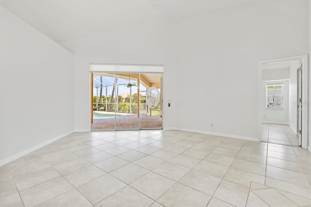 tiled empty room featuring vaulted ceiling