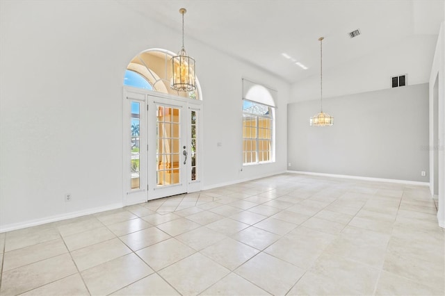 tiled spare room featuring a towering ceiling, a healthy amount of sunlight, and a notable chandelier