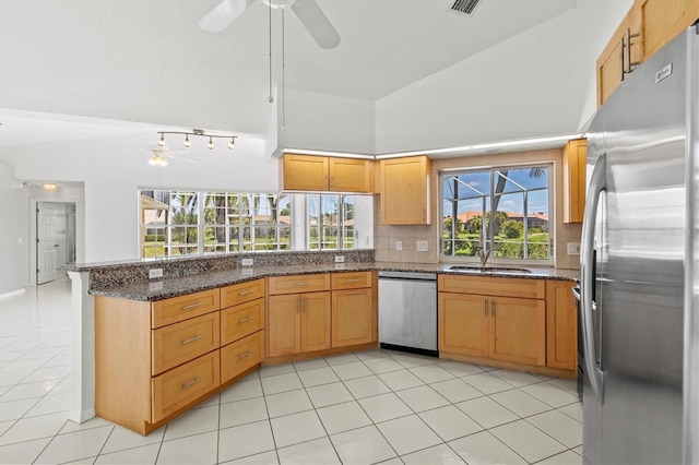 kitchen featuring sink, decorative backsplash, dark stone countertops, kitchen peninsula, and stainless steel appliances