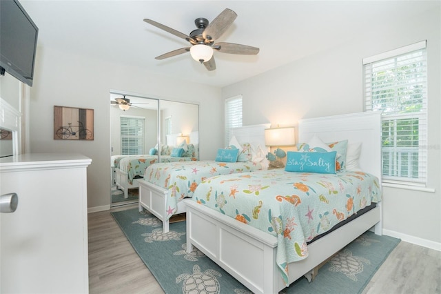 bedroom with ceiling fan, light hardwood / wood-style floors, and a closet