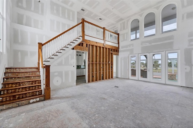 unfurnished living room with a high ceiling and french doors