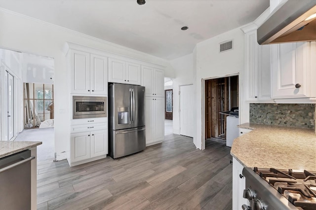 kitchen featuring backsplash, white cabinetry, light stone countertops, light hardwood / wood-style floors, and stainless steel appliances