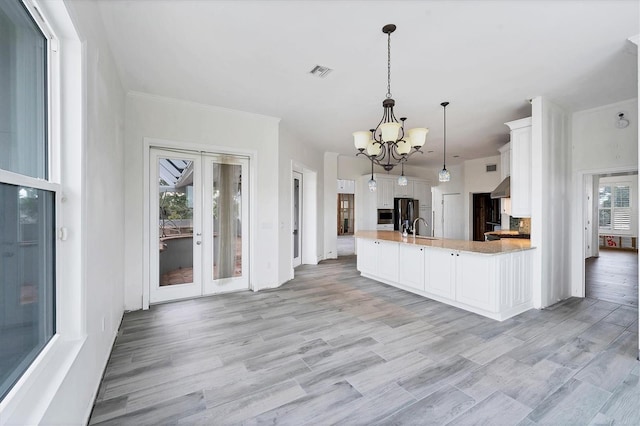 kitchen featuring light hardwood / wood-style flooring, white cabinets, black refrigerator, and pendant lighting