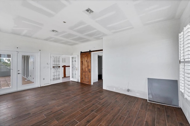 unfurnished living room with french doors, a barn door, and dark hardwood / wood-style flooring