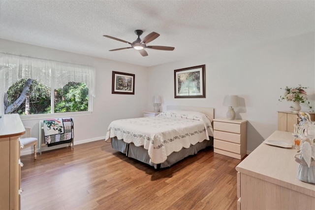 bedroom with hardwood / wood-style floors, a textured ceiling, and ceiling fan