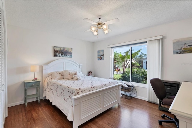 bedroom with a textured ceiling, ceiling fan, and dark hardwood / wood-style floors