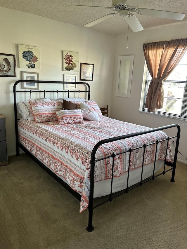 bedroom featuring ceiling fan, a textured ceiling, and dark carpet