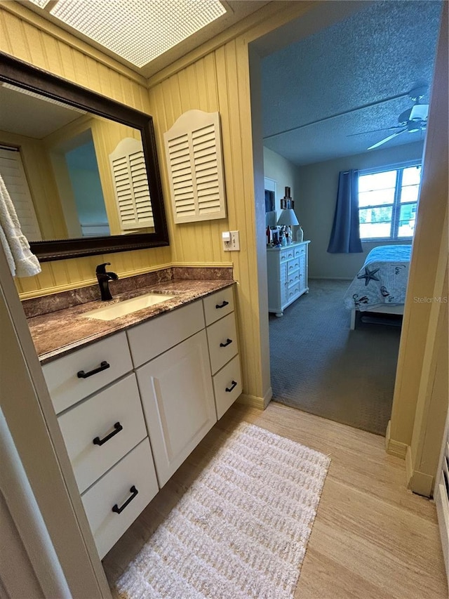 bathroom featuring vanity, ceiling fan, and wood walls