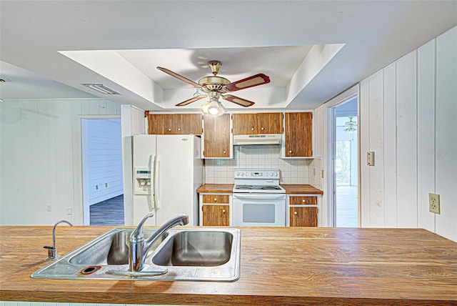 kitchen featuring white appliances, a tray ceiling, ceiling fan, and sink