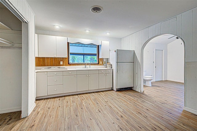 kitchen featuring white cooktop, sink, light wood-type flooring, white cabinets, and fridge