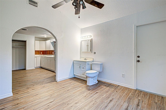 bathroom with toilet, hardwood / wood-style flooring, ceiling fan, vanity, and lofted ceiling