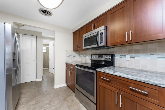 kitchen with light stone countertops, tasteful backsplash, light tile floors, and stainless steel appliances