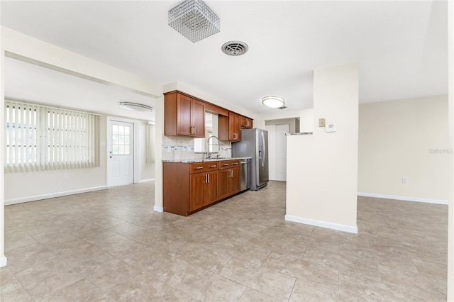 kitchen with light stone counters, stainless steel appliances, tasteful backsplash, sink, and light tile floors