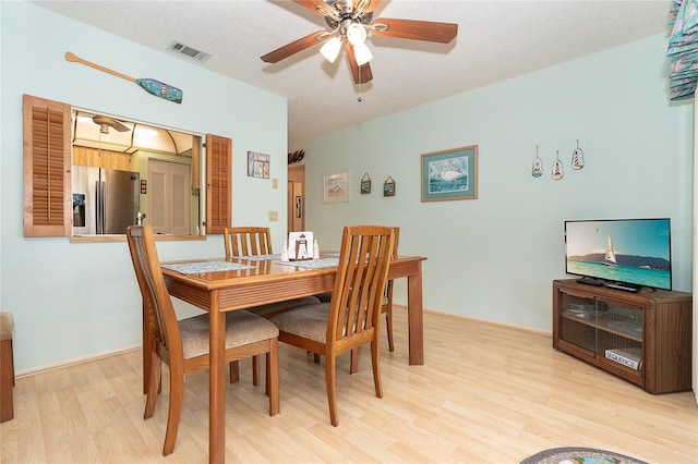 dining room featuring a textured ceiling, ceiling fan, and light wood-type flooring