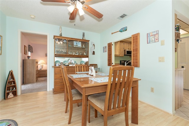 dining space featuring a textured ceiling, ceiling fan, and light hardwood / wood-style flooring