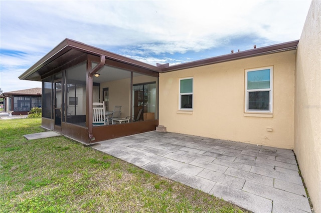 rear view of house featuring a patio area, a sunroom, and a lawn