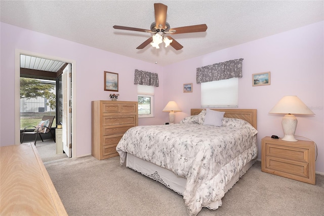 bedroom with light carpet, a textured ceiling, multiple windows, and ceiling fan