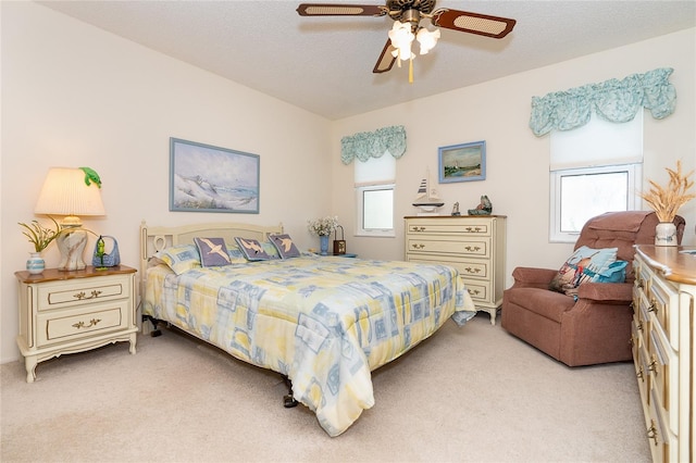 carpeted bedroom featuring a textured ceiling, multiple windows, and ceiling fan