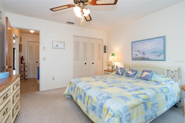 bedroom with light carpet, a closet, ceiling fan, and a textured ceiling