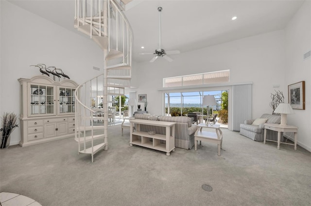 living room featuring a high ceiling, light colored carpet, and ceiling fan