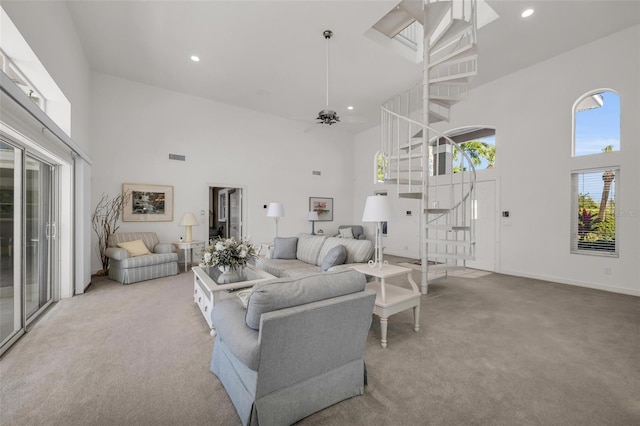 carpeted living room with ceiling fan and a high ceiling