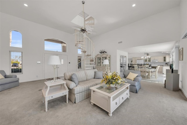 carpeted living room featuring ceiling fan and a towering ceiling