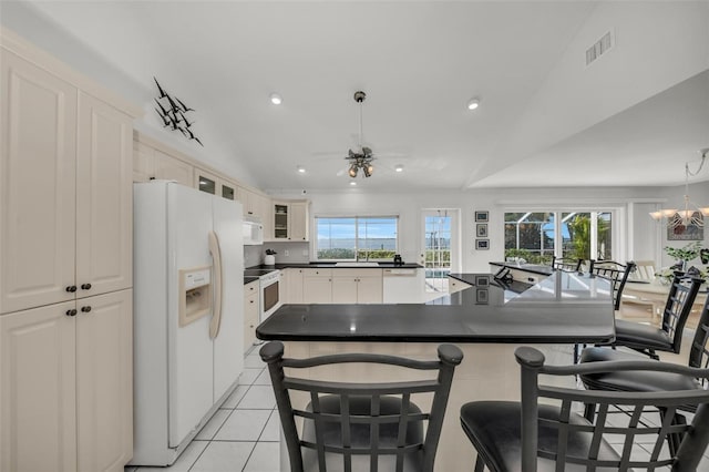 kitchen featuring ceiling fan with notable chandelier, white appliances, vaulted ceiling, and a wealth of natural light