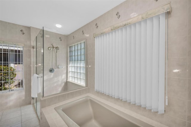 bathroom with tile patterned floors, plenty of natural light, and tile walls