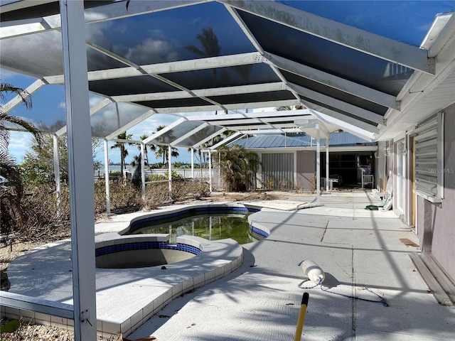 view of swimming pool featuring glass enclosure, an in ground hot tub, and a patio