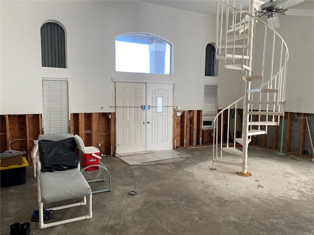 foyer with ceiling fan, concrete flooring, and a high ceiling