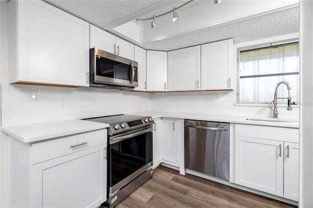 kitchen with tasteful backsplash, sink, white cabinets, stainless steel appliances, and a textured ceiling