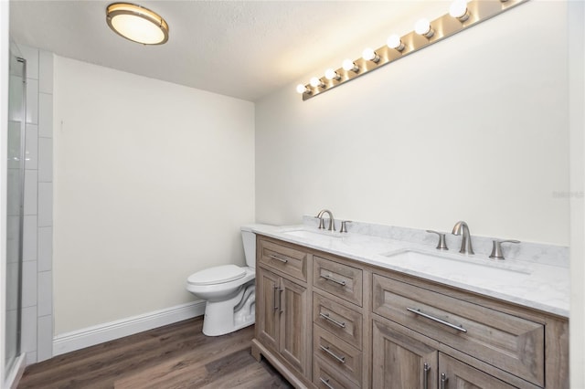 bathroom with hardwood / wood-style floors, vanity, walk in shower, toilet, and a textured ceiling