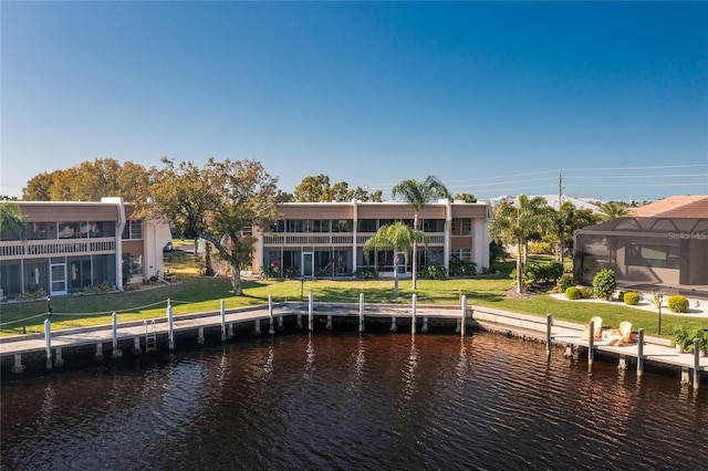 rear view of property featuring a water view, a yard, and glass enclosure