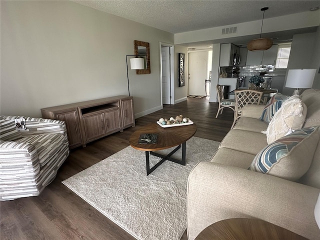 living room with a textured ceiling and dark hardwood / wood-style flooring