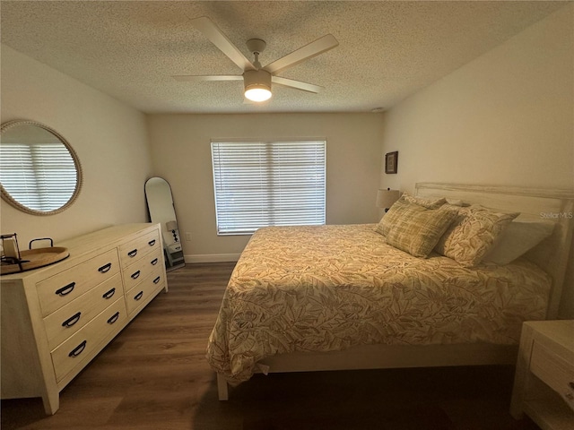 bedroom featuring dark wood-type flooring, a textured ceiling, and ceiling fan