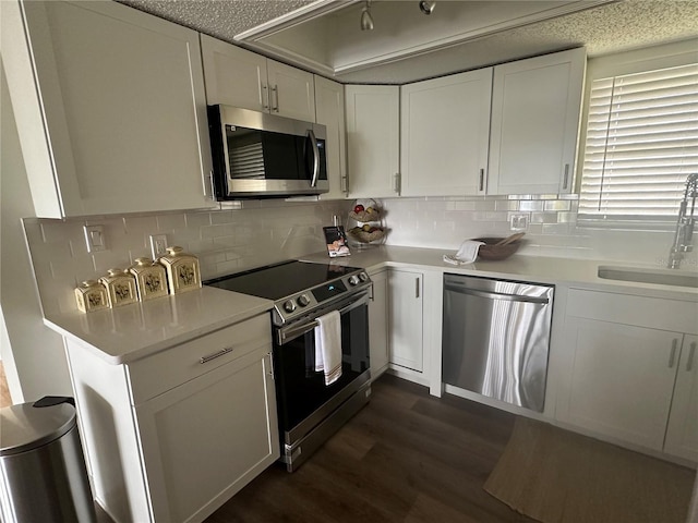 kitchen featuring tasteful backsplash, white cabinetry, sink, stainless steel appliances, and dark wood-type flooring