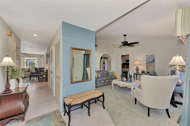 carpeted living room with a textured ceiling and ceiling fan