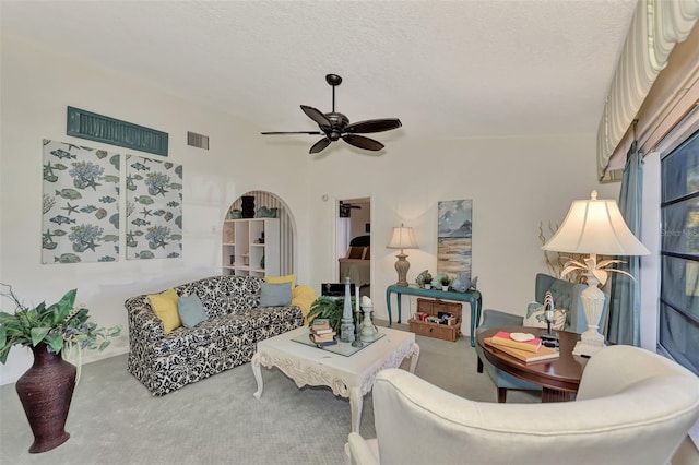 carpeted living room with ceiling fan and a textured ceiling