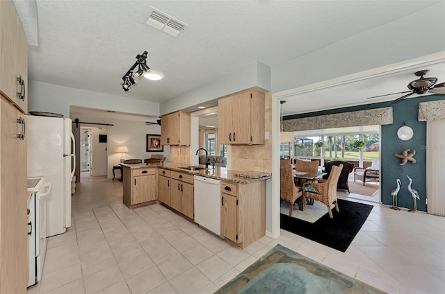 kitchen featuring ceiling fan, white appliances, a barn door, sink, and light tile floors