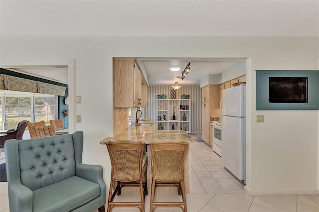 kitchen featuring light brown cabinetry, kitchen peninsula, white appliances, backsplash, and light tile flooring