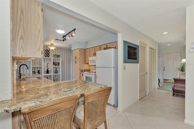 kitchen featuring kitchen peninsula, white appliances, sink, light tile floors, and rail lighting