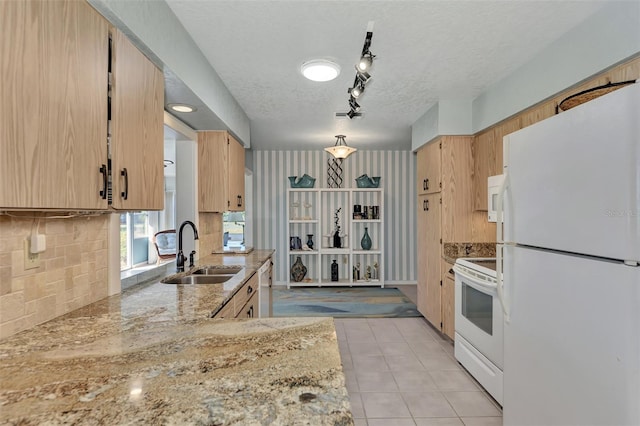 kitchen with a textured ceiling, rail lighting, light brown cabinetry, white appliances, and sink