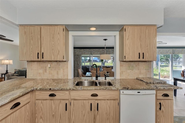 kitchen featuring white dishwasher, tasteful backsplash, sink, and light stone countertops