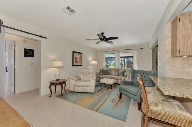 tiled living room featuring a barn door and ceiling fan