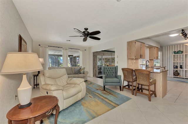 tiled living room featuring plenty of natural light, ceiling fan, and sink