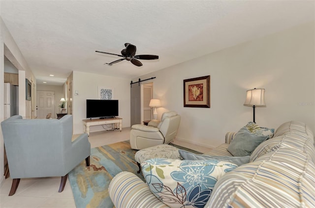 tiled living room featuring a barn door and ceiling fan