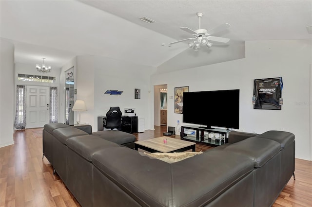 living room featuring ceiling fan with notable chandelier, vaulted ceiling, and light hardwood / wood-style flooring