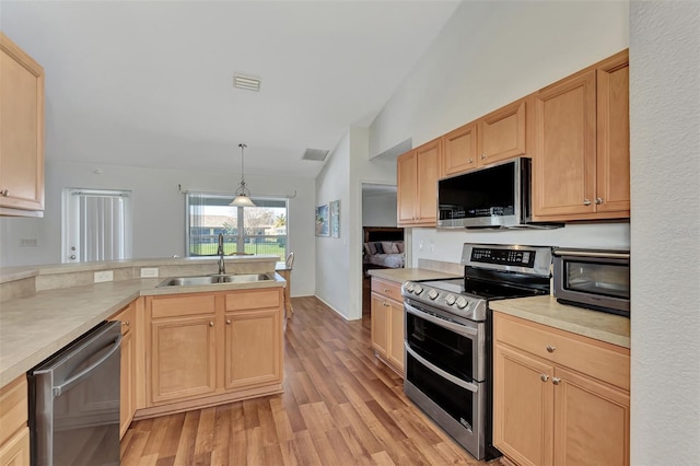 kitchen featuring decorative light fixtures, light wood-type flooring, sink, and stainless steel appliances