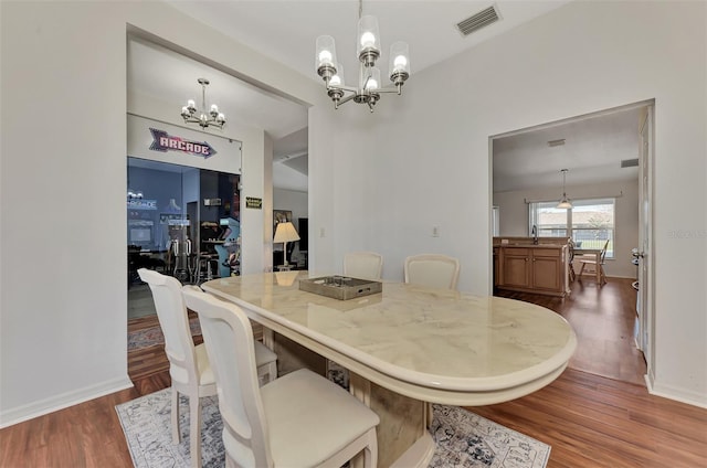 dining area with a notable chandelier, dark wood-type flooring, and sink